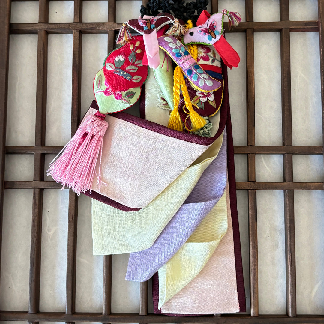 Colorful traditional fabric hanging against a wooden lattice background