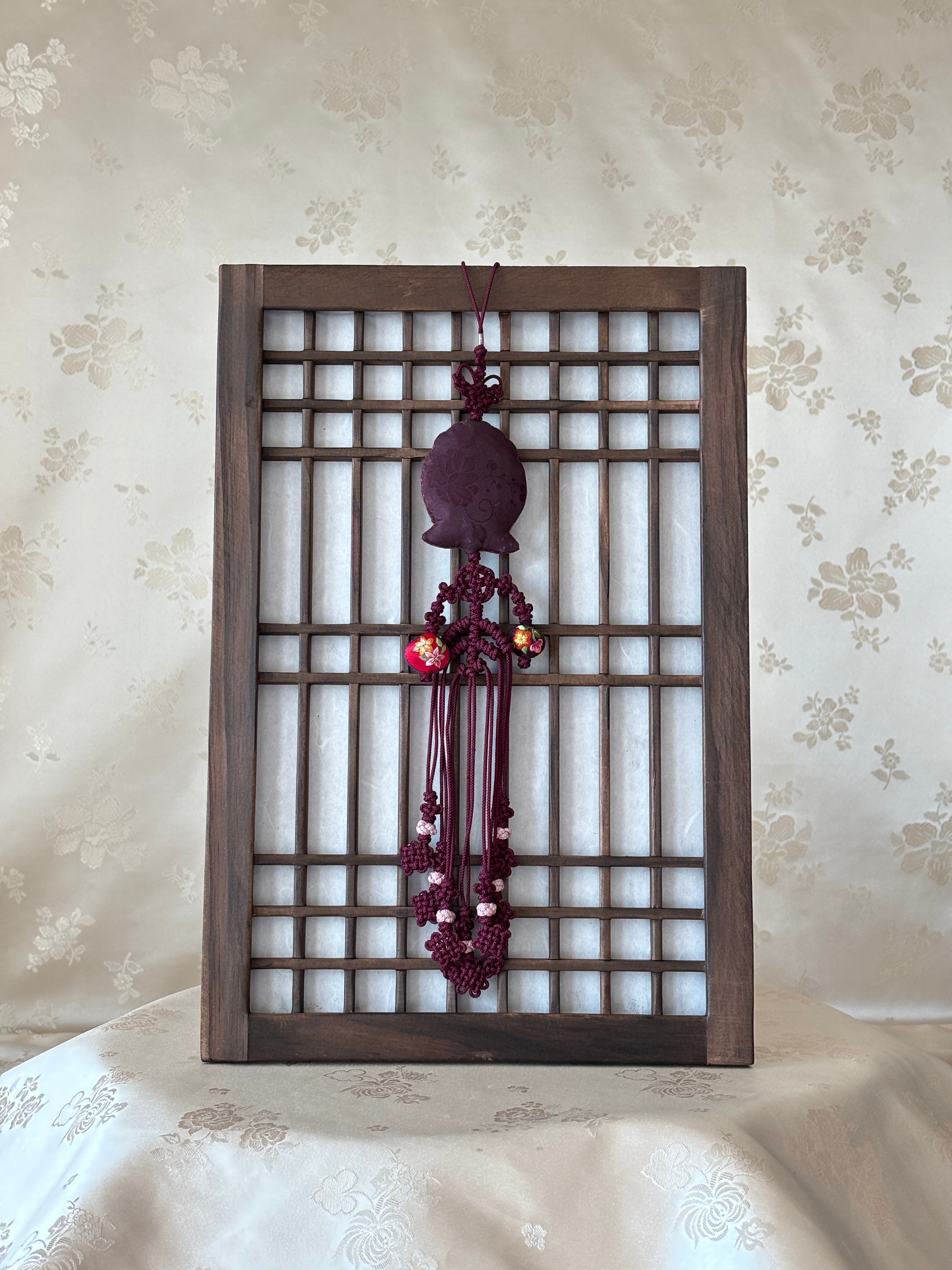 Decorative wall art with a wooden lattice design and purple floral elements on a floral wallpaper background.