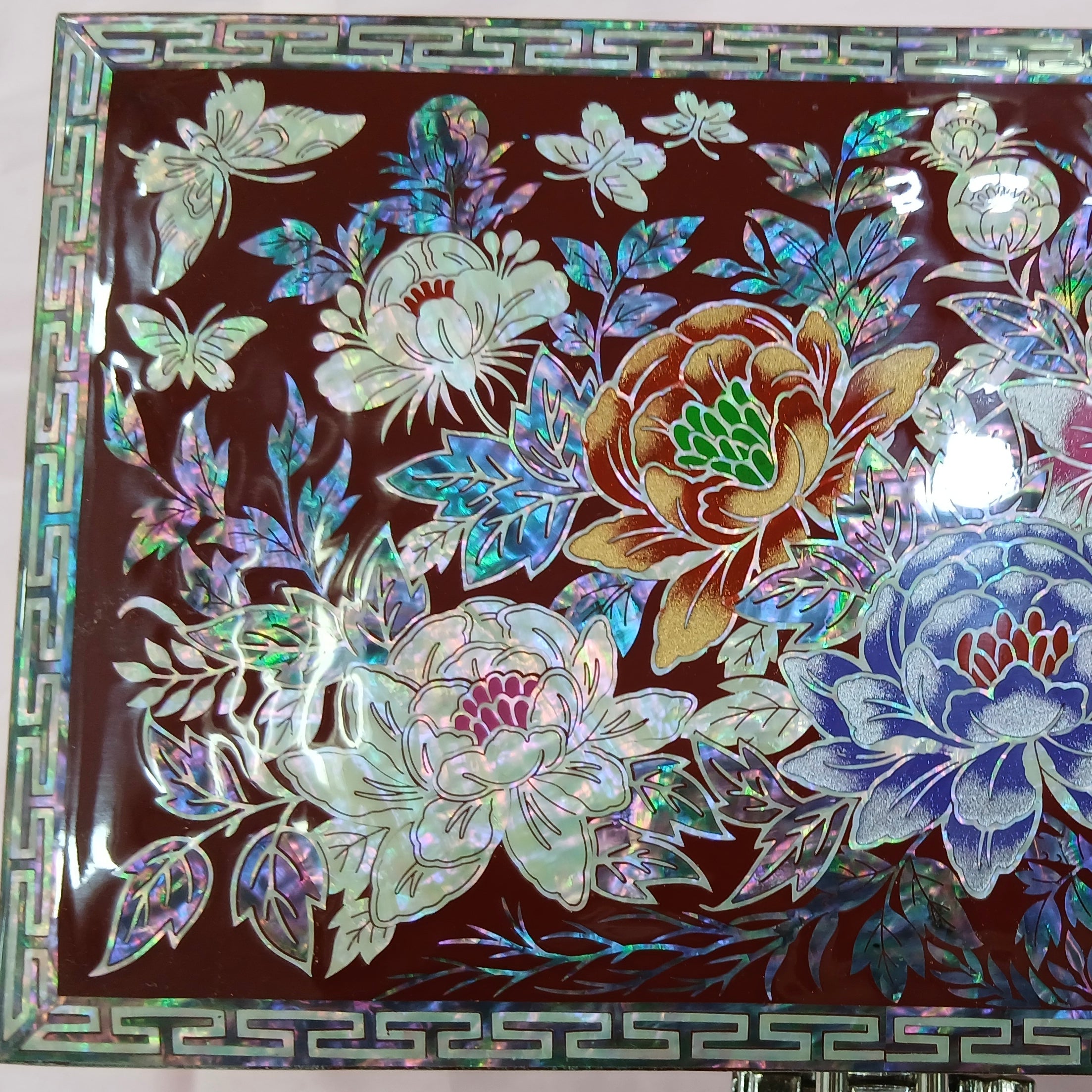 Decorative jewelry box with floral and butterfly designs on a red background