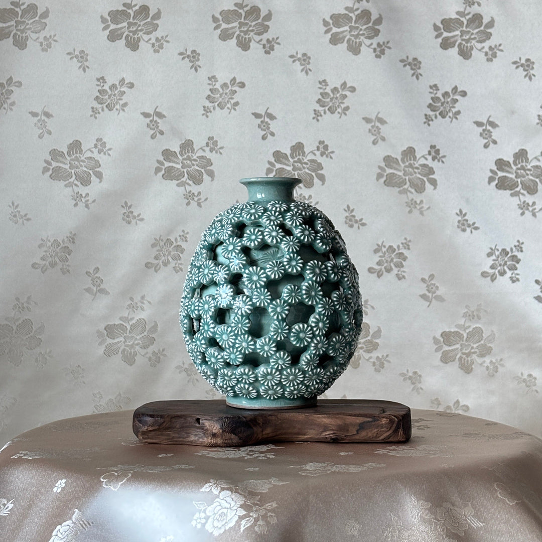 Decorative vase with intricate design on a floral-patterned celadon background
