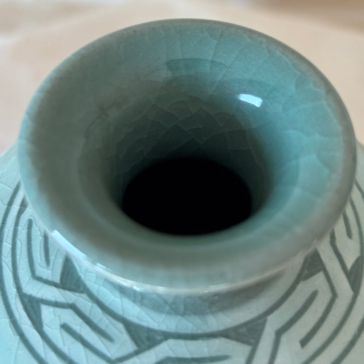 Ceramic vase with cracked surface and geometric patterns on a beige background