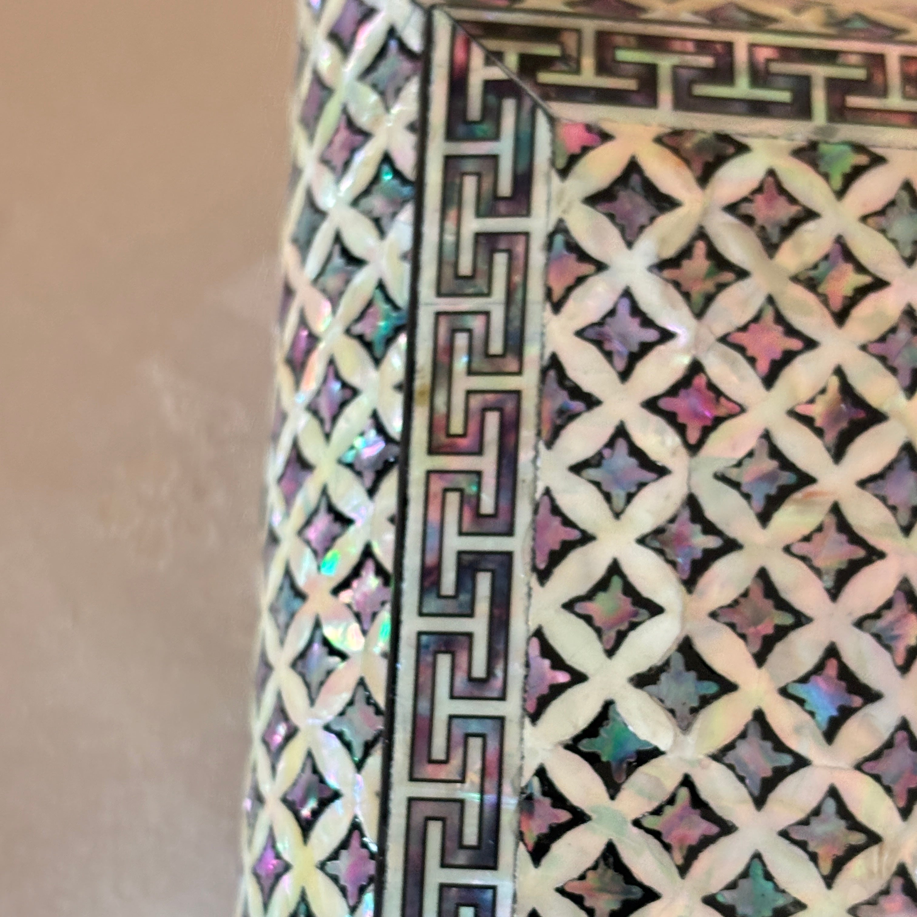 mother of pearl with intricate geometric pattern on a beige background