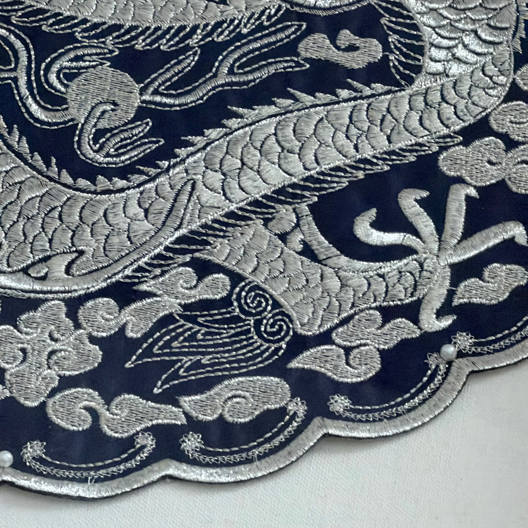 Close-up of silver embroidered pattern on a dark blue fabric background