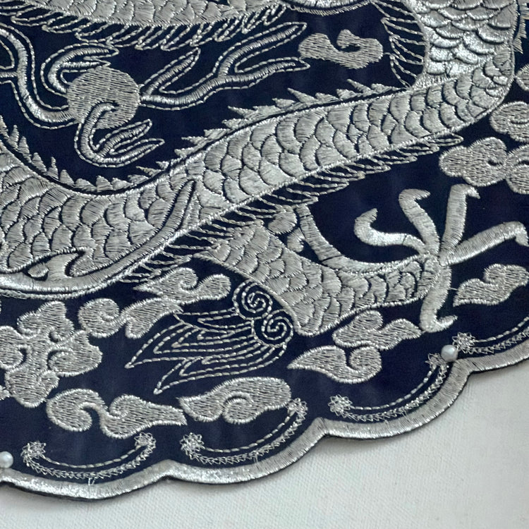 Close-up of silver embroidered pattern on a dark blue fabric background