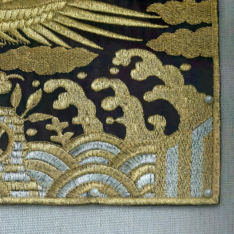 Close-up of embroidered fabric with gold and silver patterns on a black background