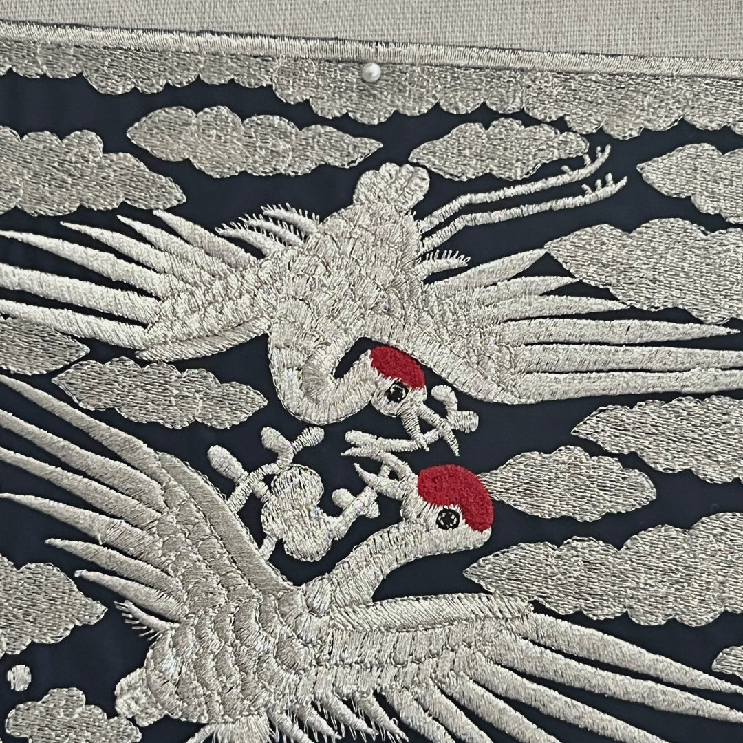 Embroidered design of cranes on a dark background