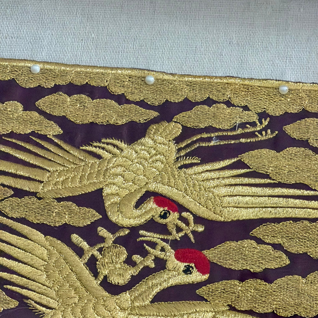 Embroidered design of a phoenix on purple fabric with gold thread