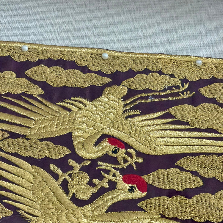 Embroidered design of a phoenix on purple fabric with gold thread