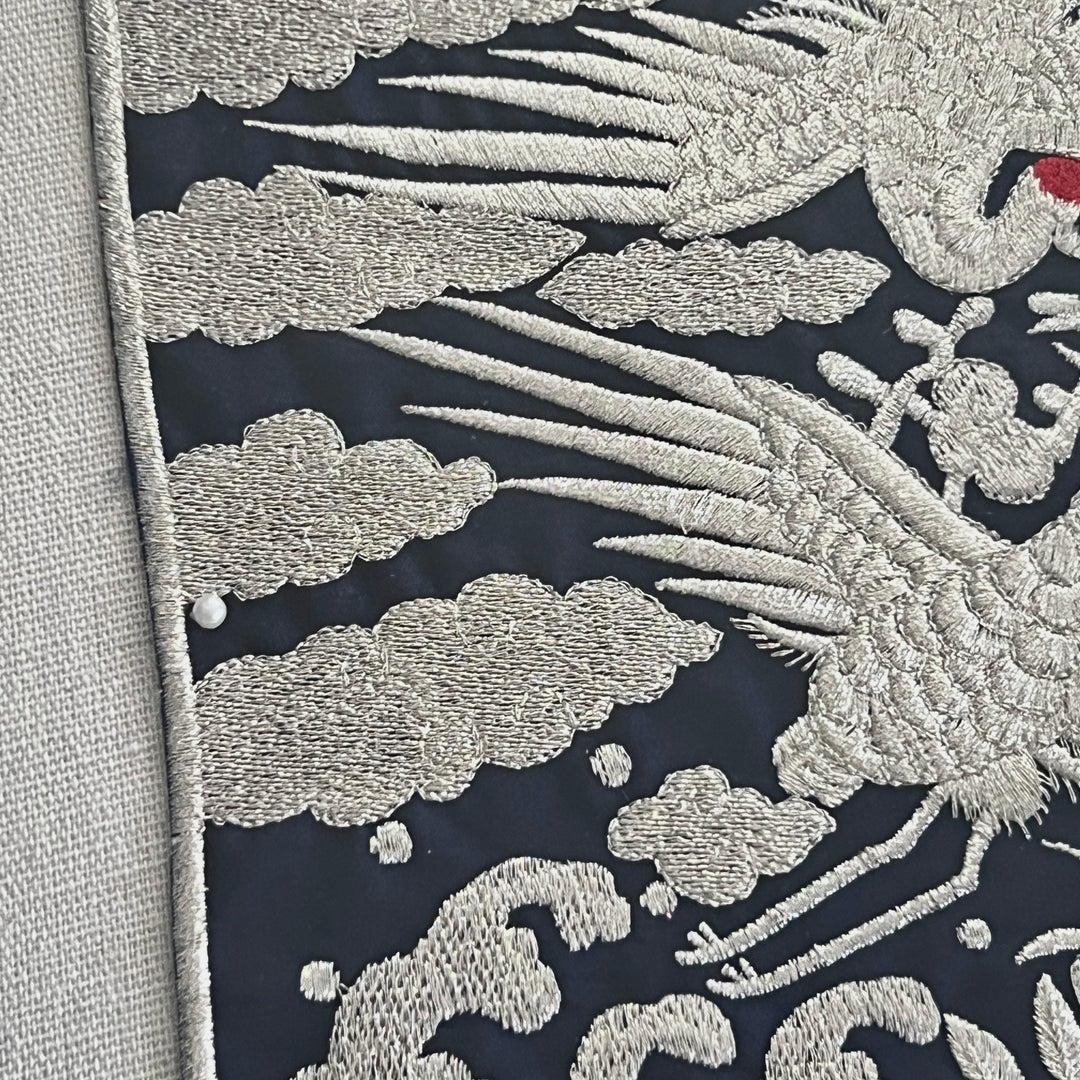 Embroidered fabric with silver dragon design on a dark background