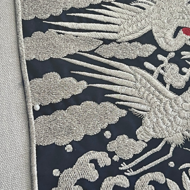 Embroidered fabric with silver dragon design on a dark background
