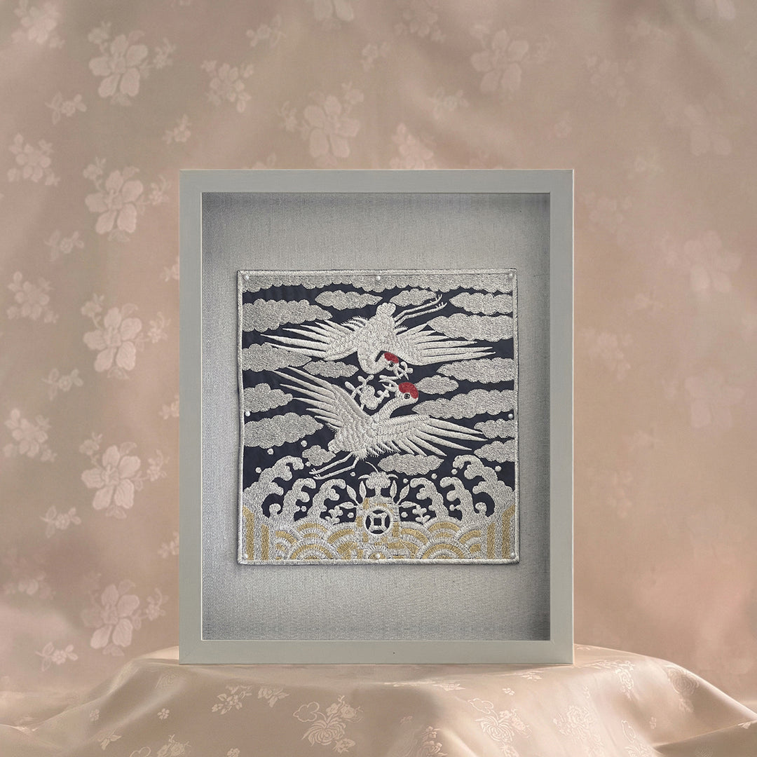 Framed artwork of a white bird with red accents on a patterned wall.