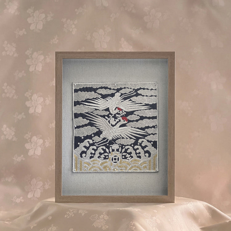 Framed artwork of a crane on a textured wall with floral patterns