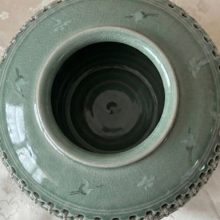 Green ceramic vase with intricate patterns on a light background