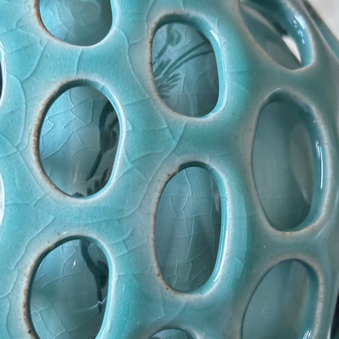 Close-up of a ceramic product with circular holes and textured surface.