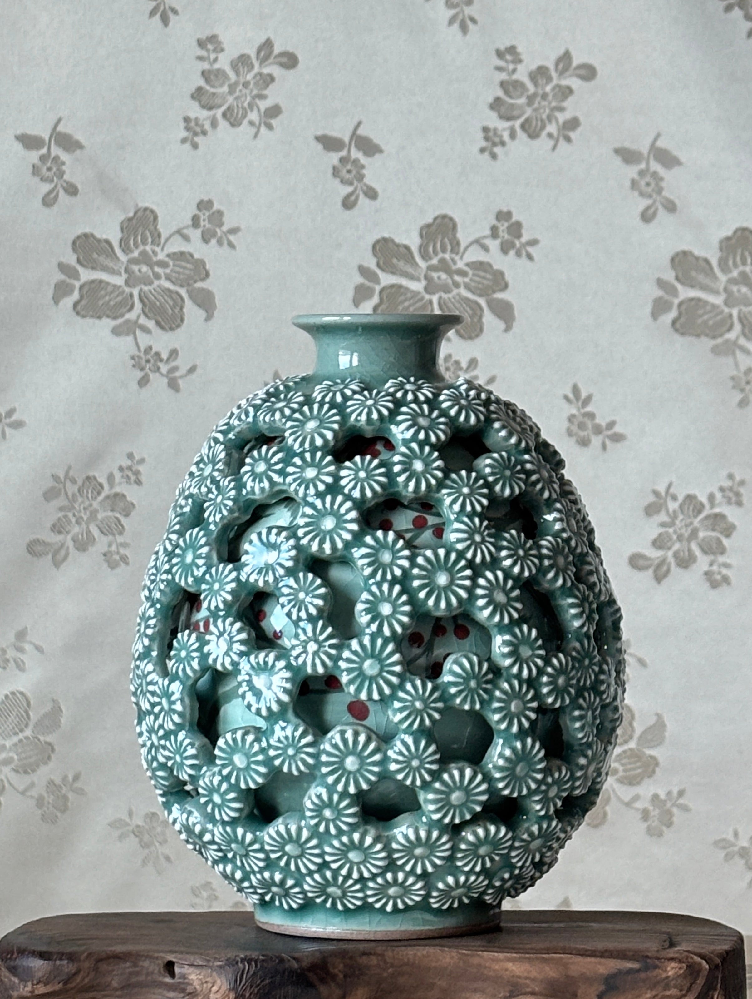 Decorative vase with floral pattern on a floral wallpaper background