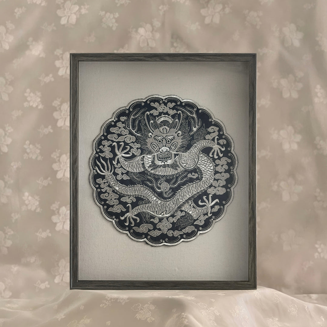 Framed artwork of a dragon design on a floral wallpaper background