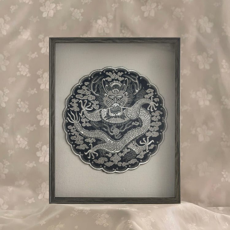 Framed artwork of a dragon design on a floral wallpaper background