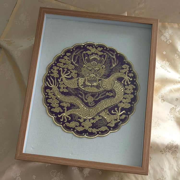 Framed artwork with a gold dragon design on a purple background