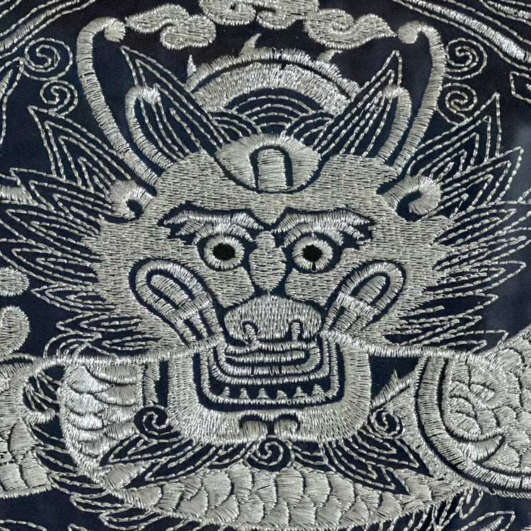 Embroidered dragon design on a dark fabric background