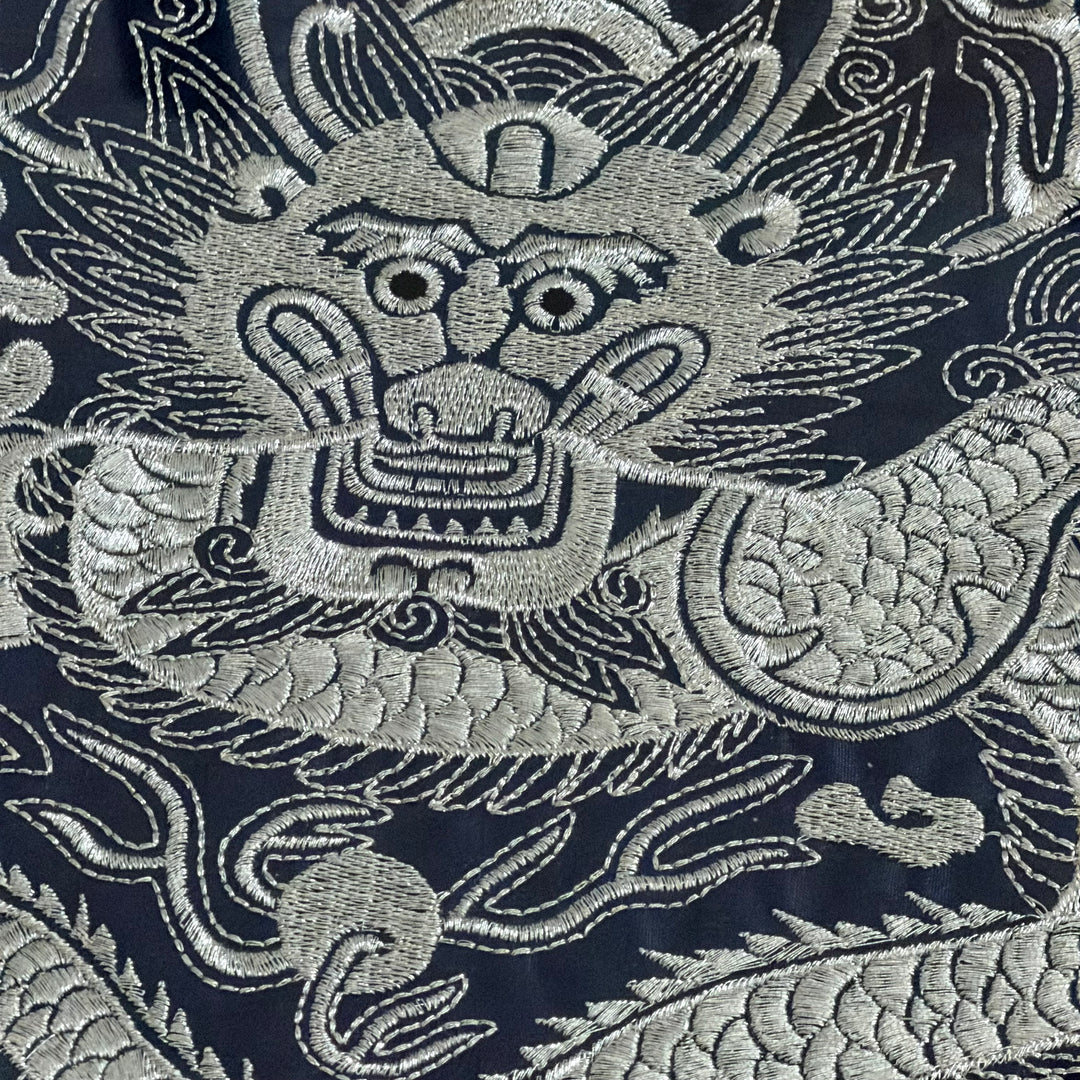 Close-up of an embroidered dragon design on fabric with a dark background