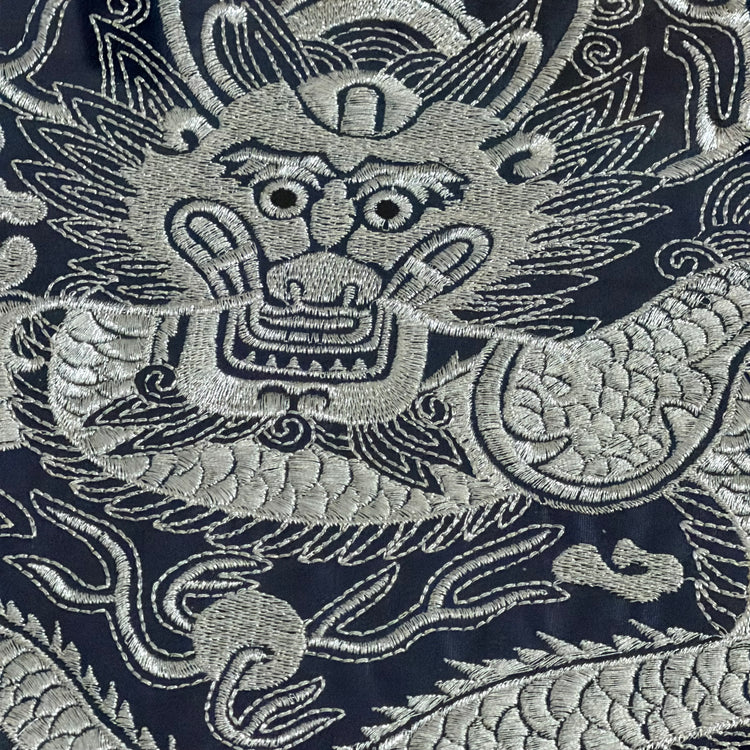 Close-up of an embroidered dragon design on fabric with a dark background