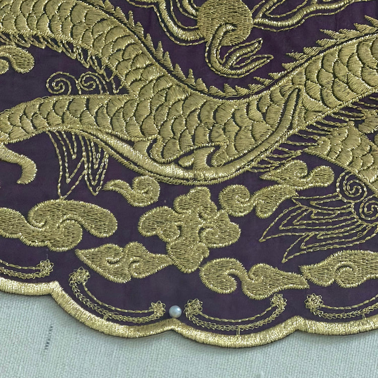 Embroidered dragon design on purple fabric