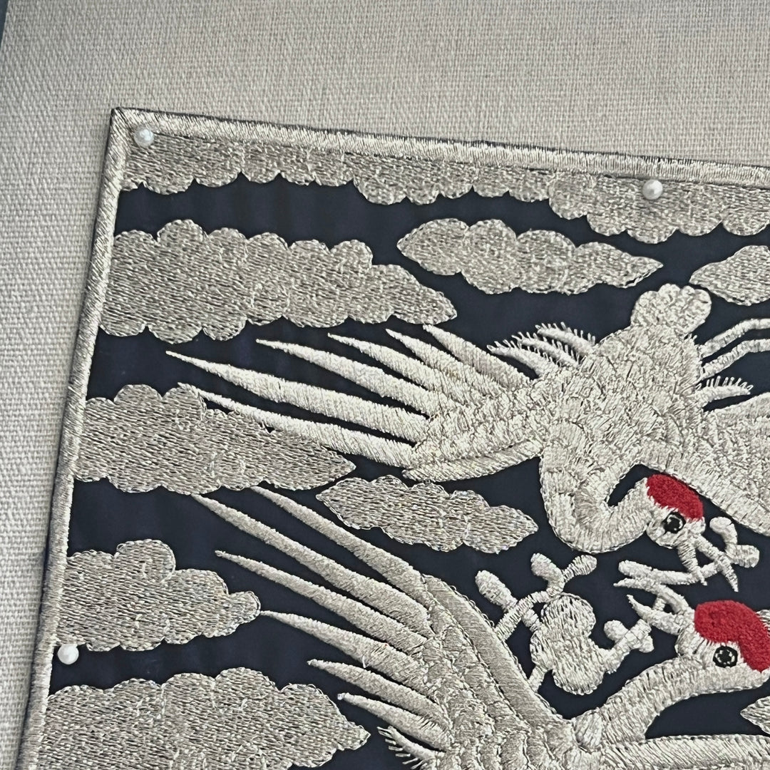 Embroidered design of a phoenix with clouds on a dark background