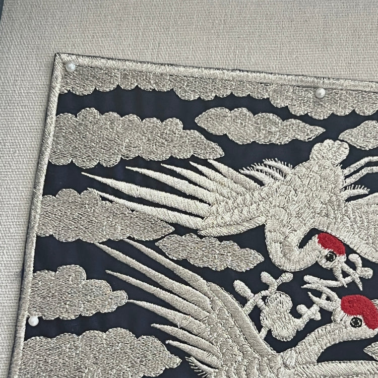 Embroidered design of a phoenix with clouds on a dark background