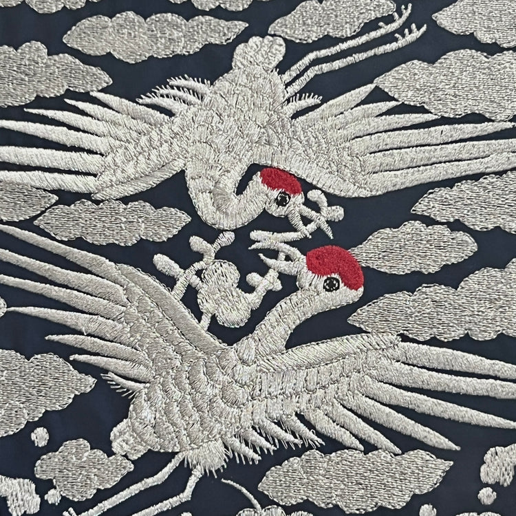 Embroidered design of cranes on a dark background