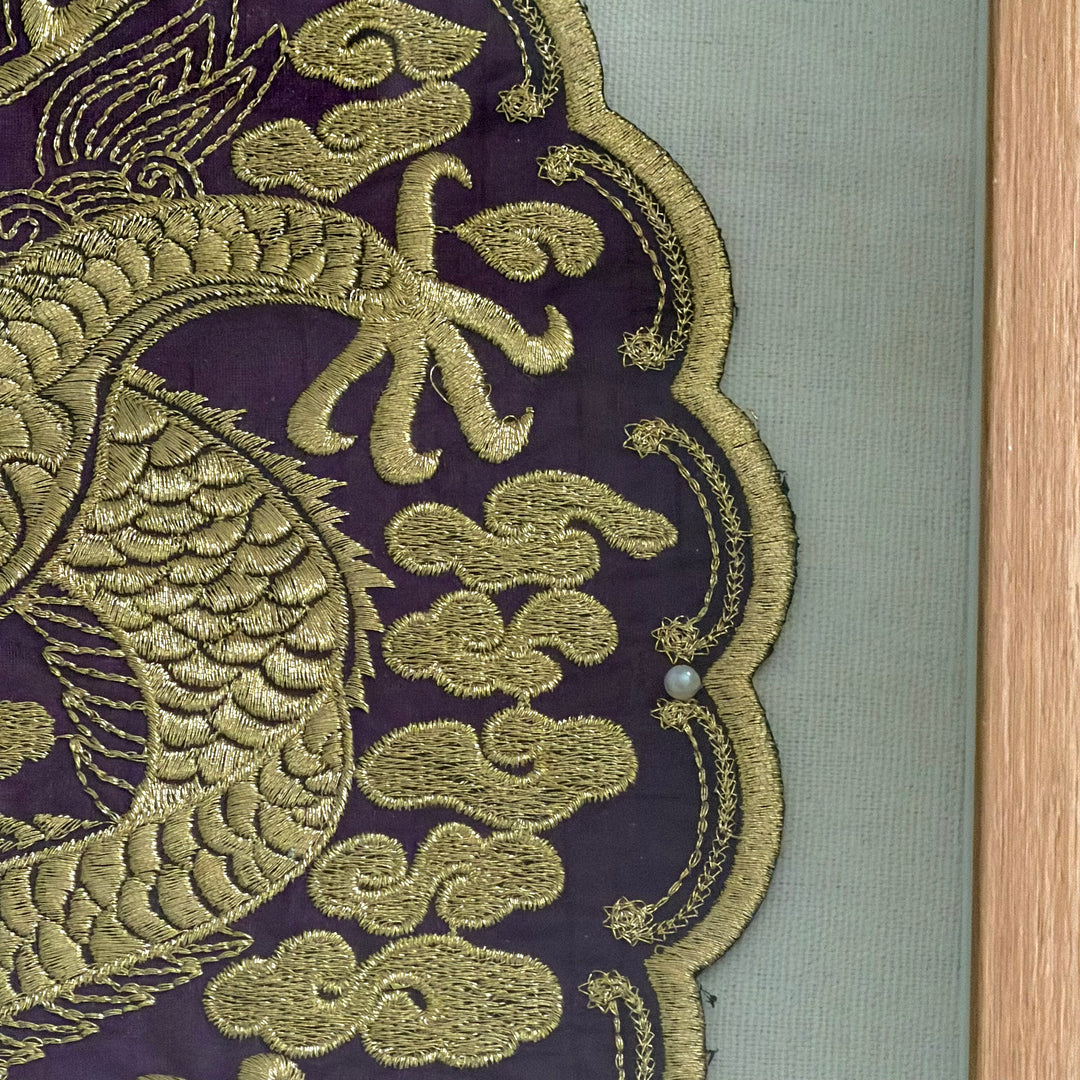 Close-up of gold embroidered dragon design on purple fabric