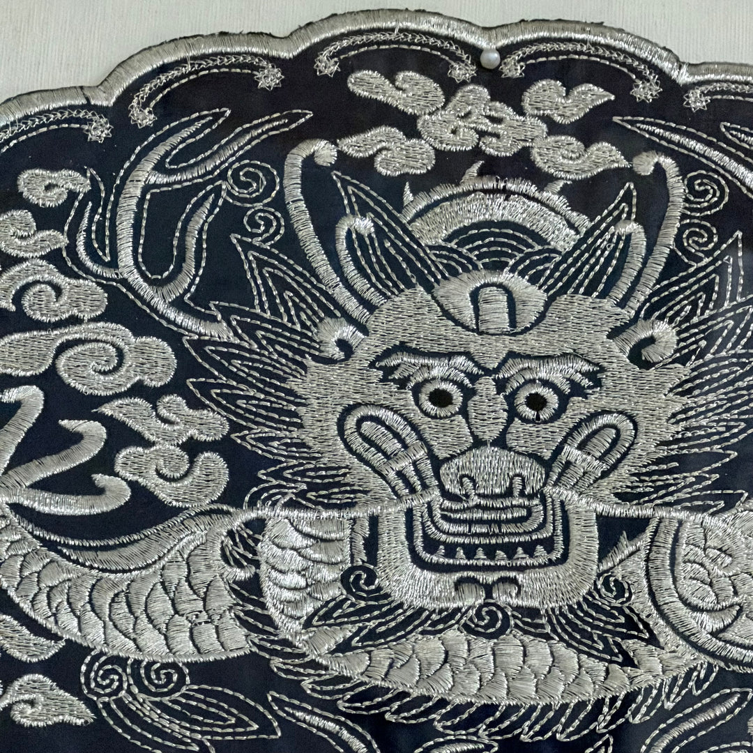 Embroidered dragon design on a dark fabric background