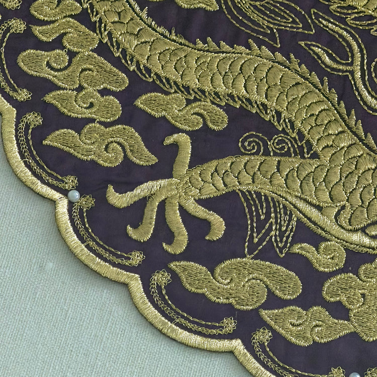 Close-up of gold embroidered dragon design on a dark fabric background