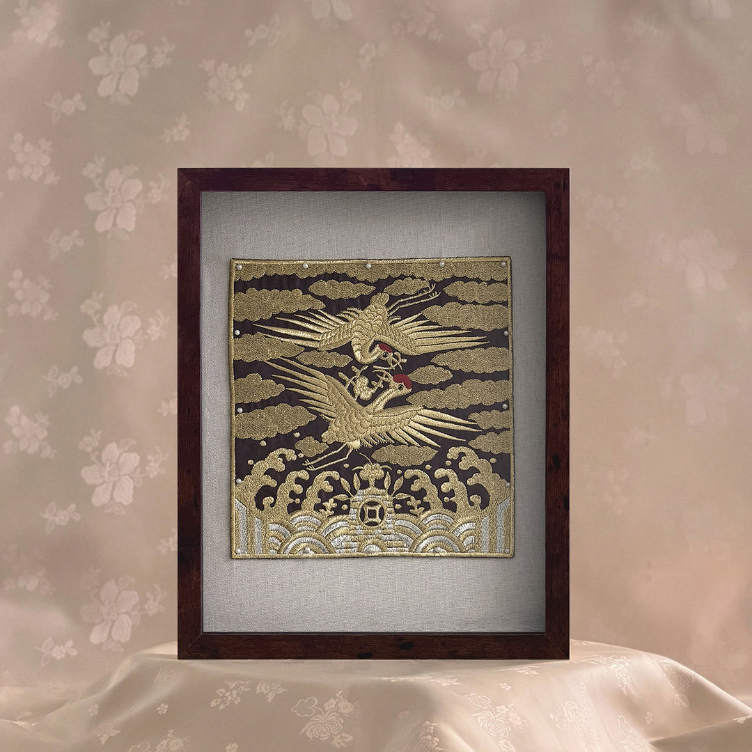 Framed artwork with a gold and white design on a floral wallpaper background
