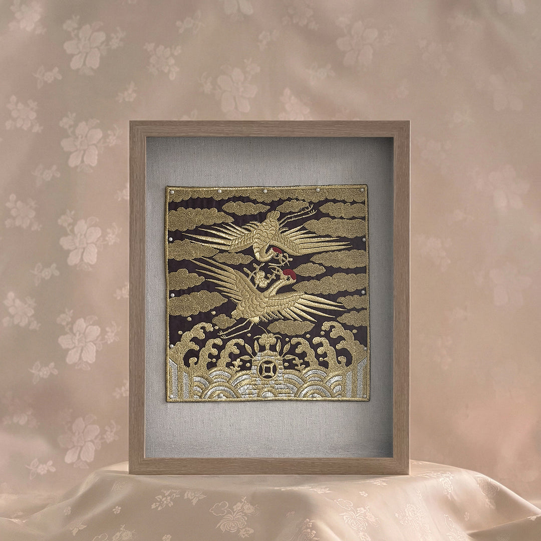 Framed artwork with a gold and black design on a floral wallpaper background