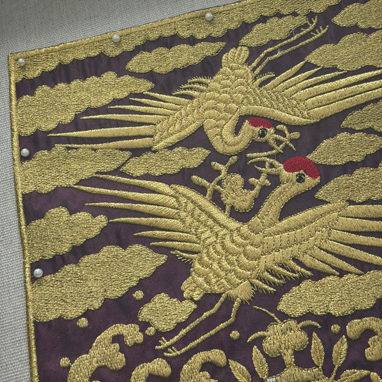 Embroidered fabric with gold phoenix design on a dark background