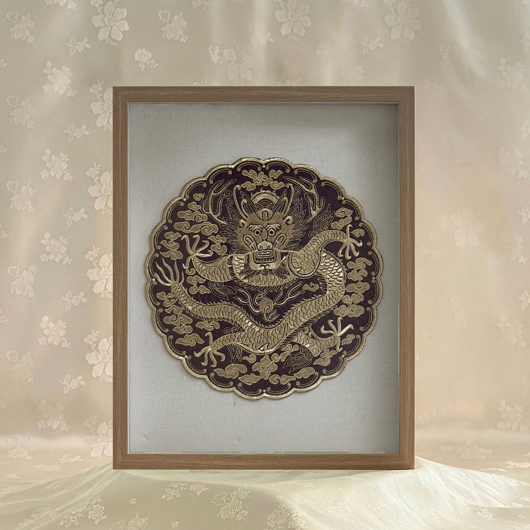 Decorative wall art with a dragon design in a wooden frame on a floral wallpaper background