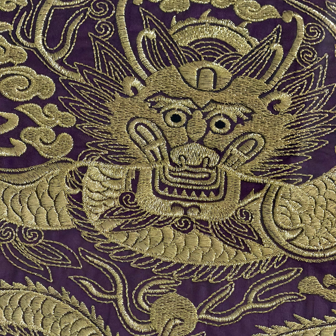 Embroidered dragon design on a purple fabric background