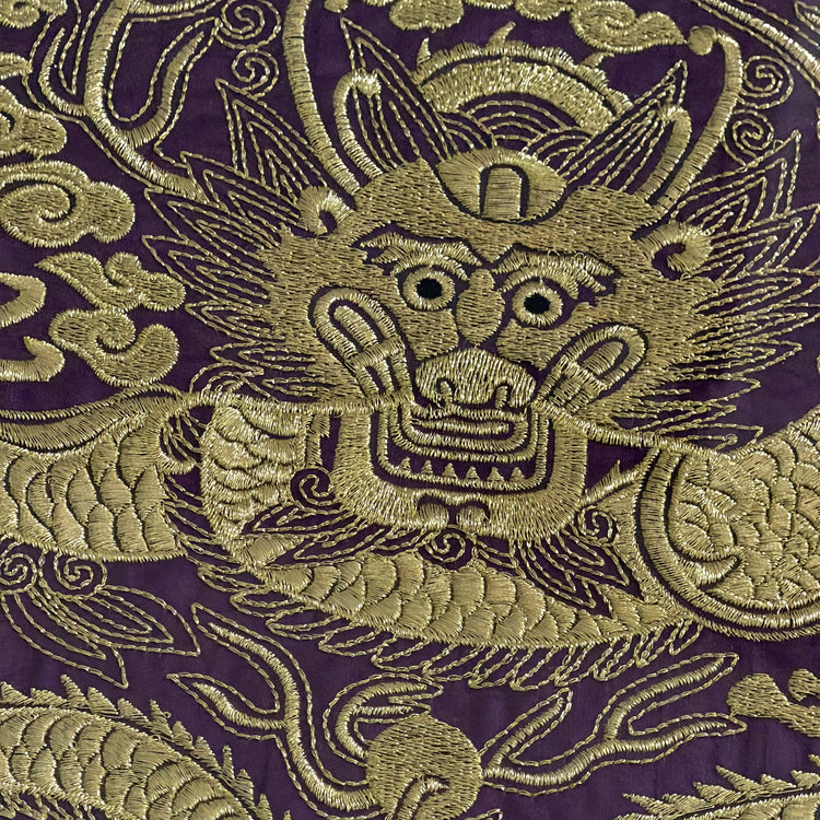Embroidered dragon design on a purple fabric background