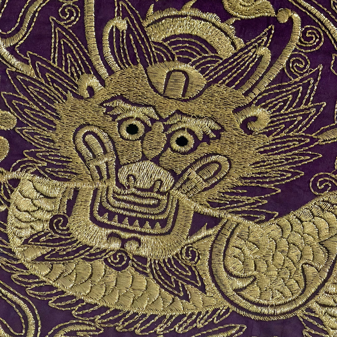 Embroidered dragon design on purple fabric