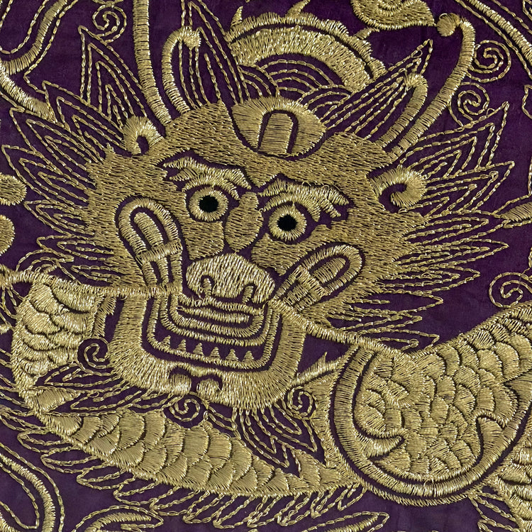 Embroidered dragon design on purple fabric