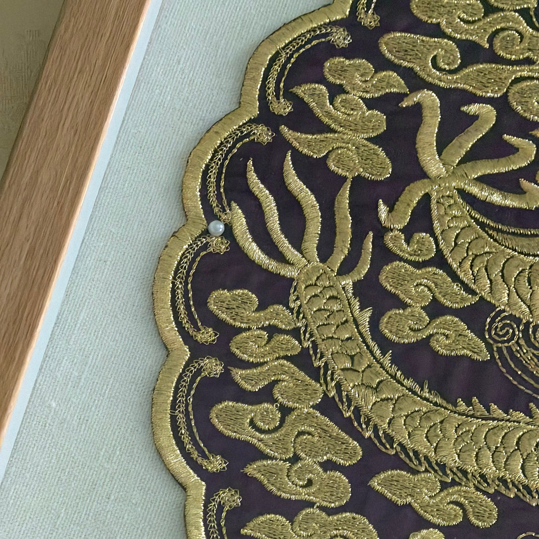 Close-up of gold embroidered dragon design on a dark fabric background