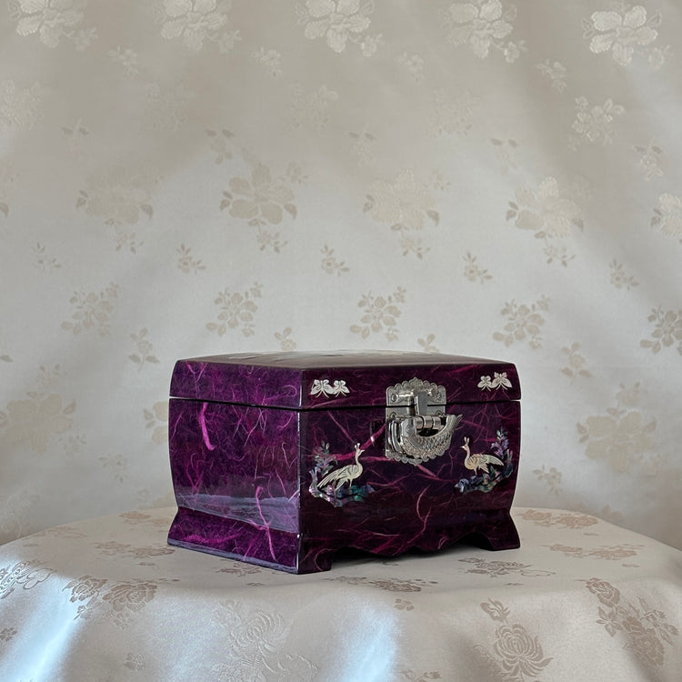 Decorative purple jewelry box with intricate designs on a floral-patterned surface.
