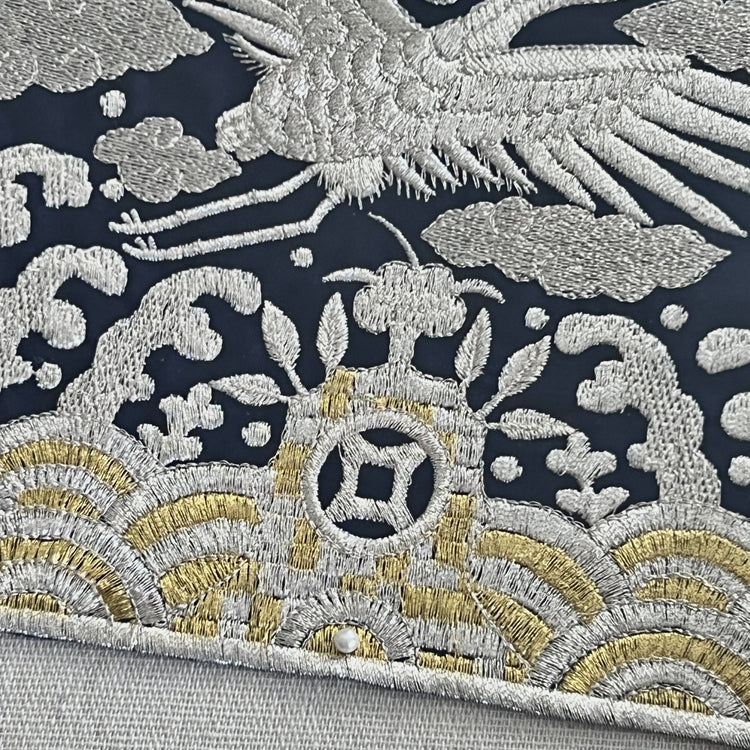 Close-up of intricate embroidered fabric with floral and bird design on a dark background