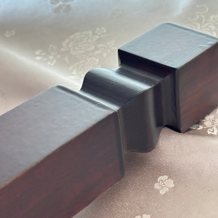 Close-up of a dark wooden furniture leg on a floral-patterned fabric background