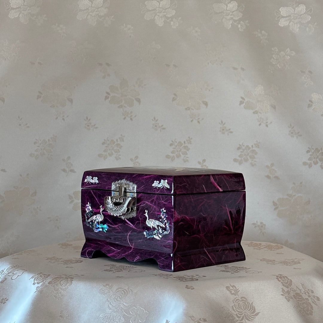 Purple jewelry box with silver accents on a floral-patterned surface