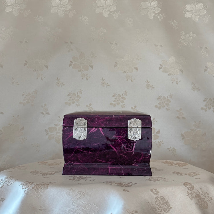 Purple marbled jewelry box with silver accents on a floral-patterned surface