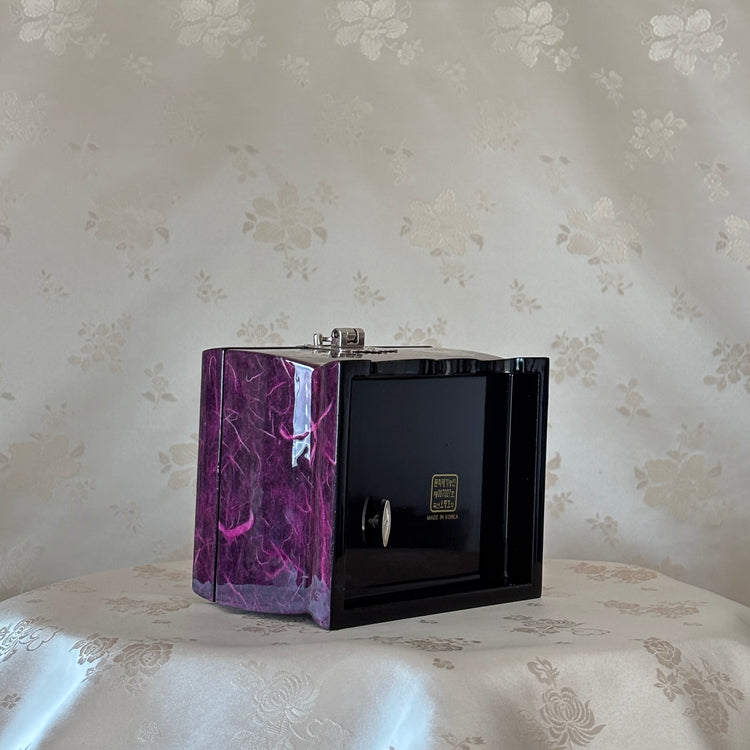 Black and purple marbled jewelry box on a floral-patterned surface