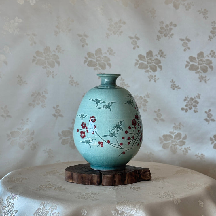 celadon vase with floral design on a wooden stand