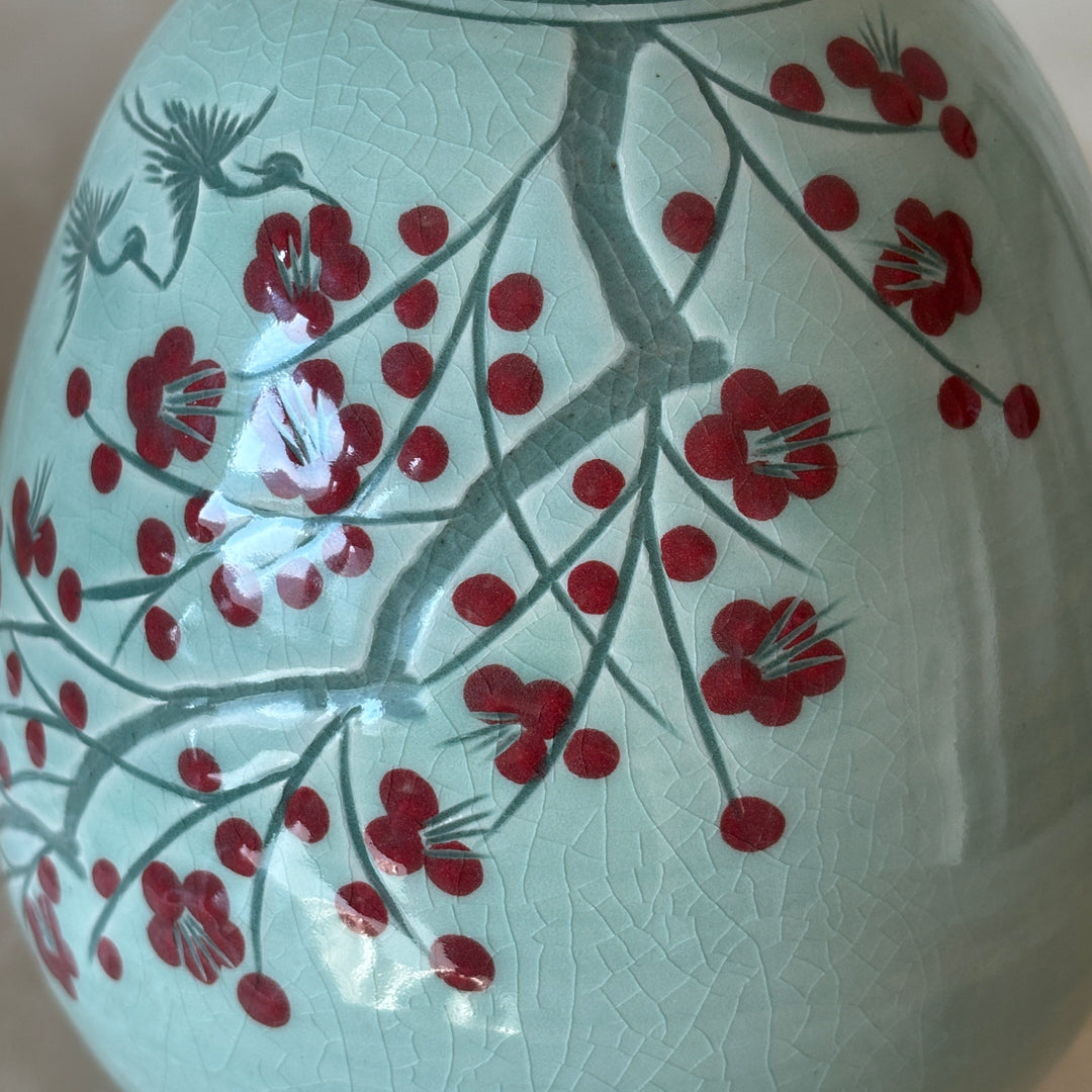 Decorative vase with red floral design on a light background