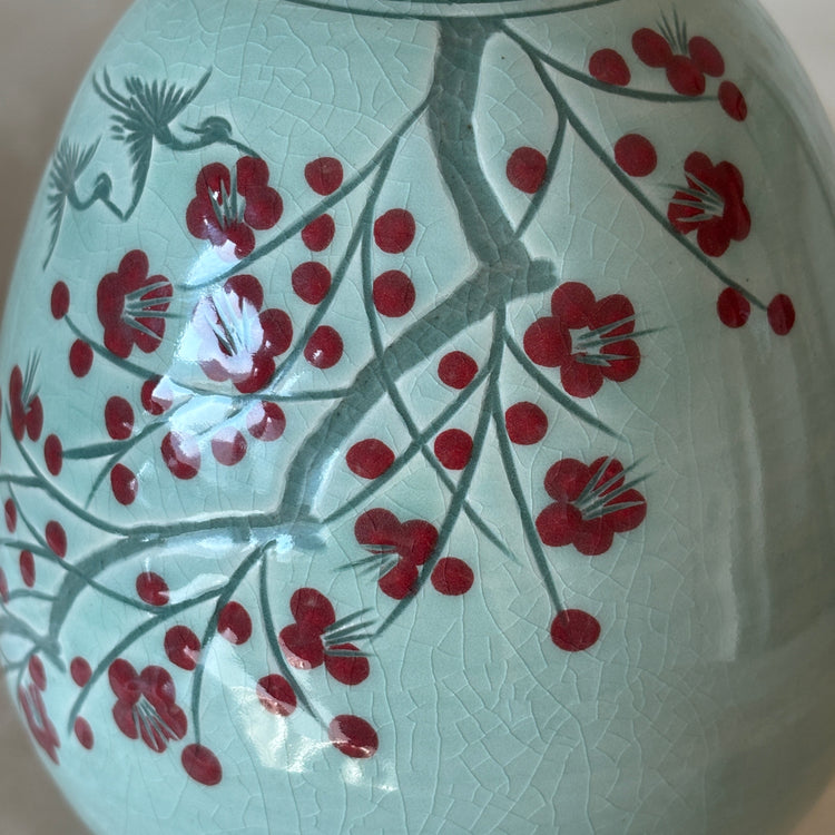 Decorative vase with red floral design on a light background